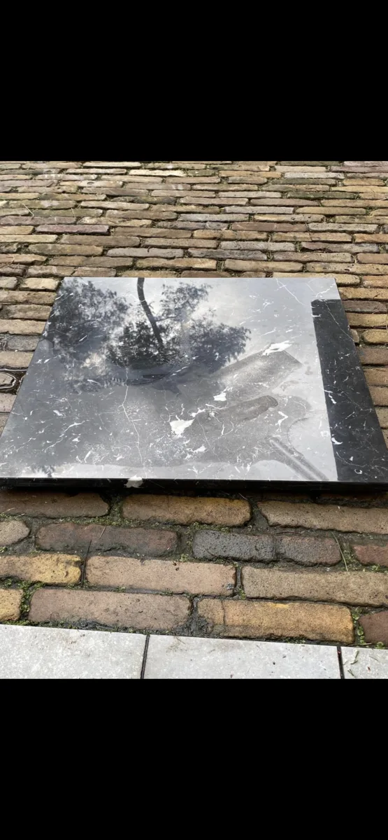 Rond zwartmarmeren tafelblad met lichte vlek voor de behandeling